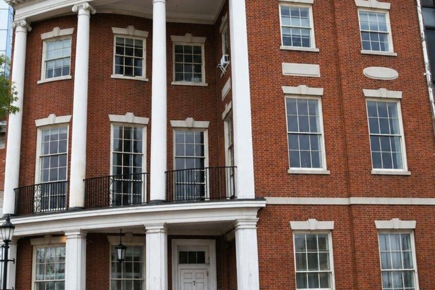 A red brick building with white trim, multiple windows, and a white door. 3