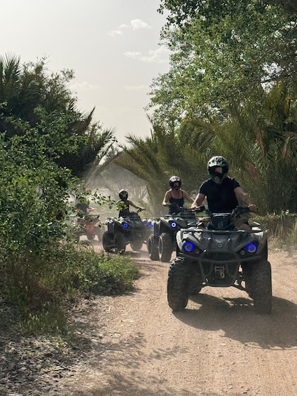 A group of people riding ATVs on a dirt path surrounded by greenery. 3