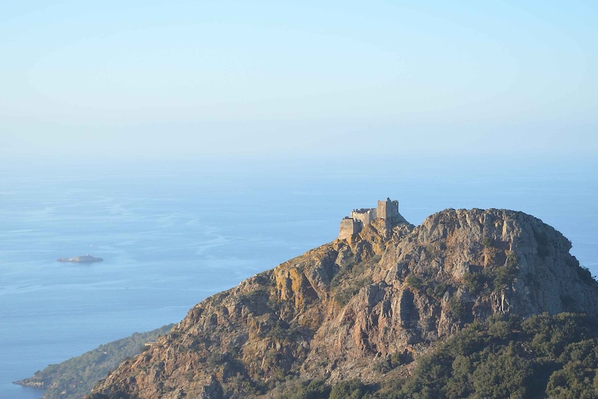 A rugged mountain with a castle on top, overlooking a vast body of water. 1