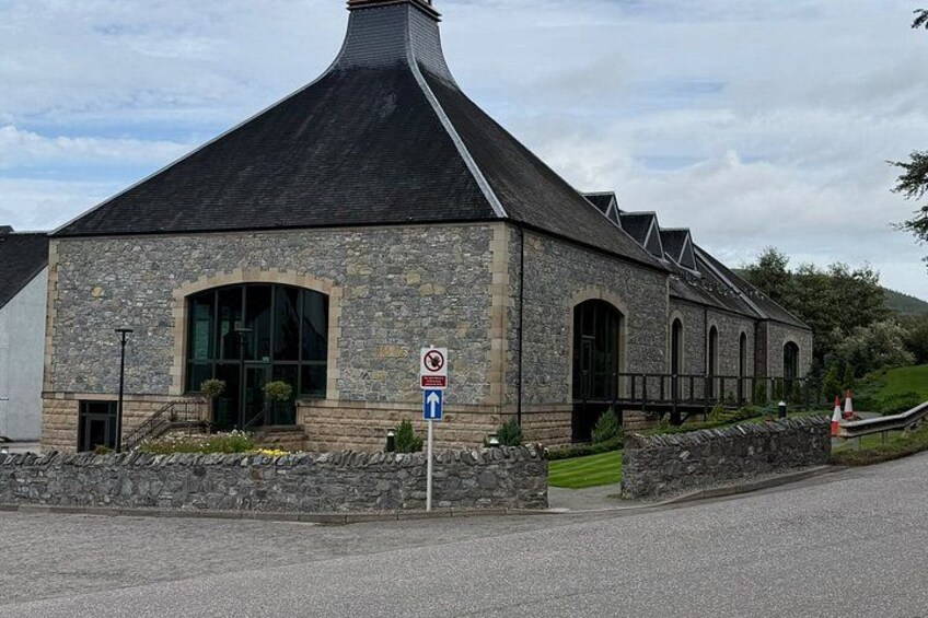 A stone building with a pointed roof and a blue directional sign. 3