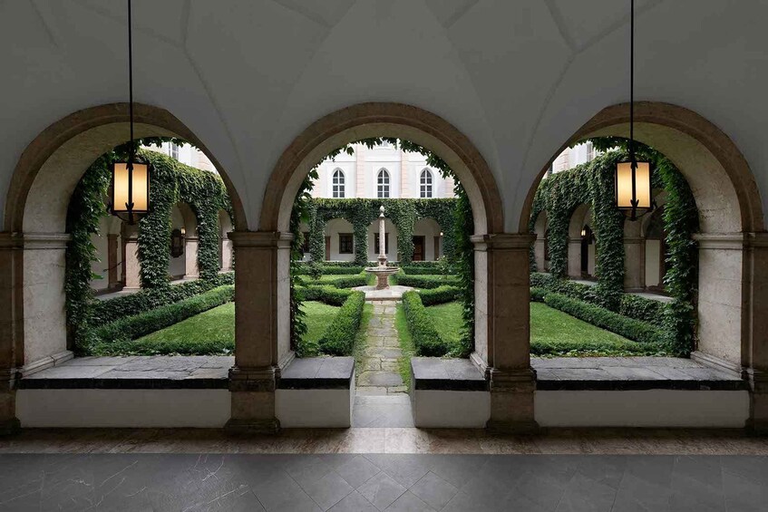 Un patio con tres arcadas, una fuente central y un edificio al fondo. 4