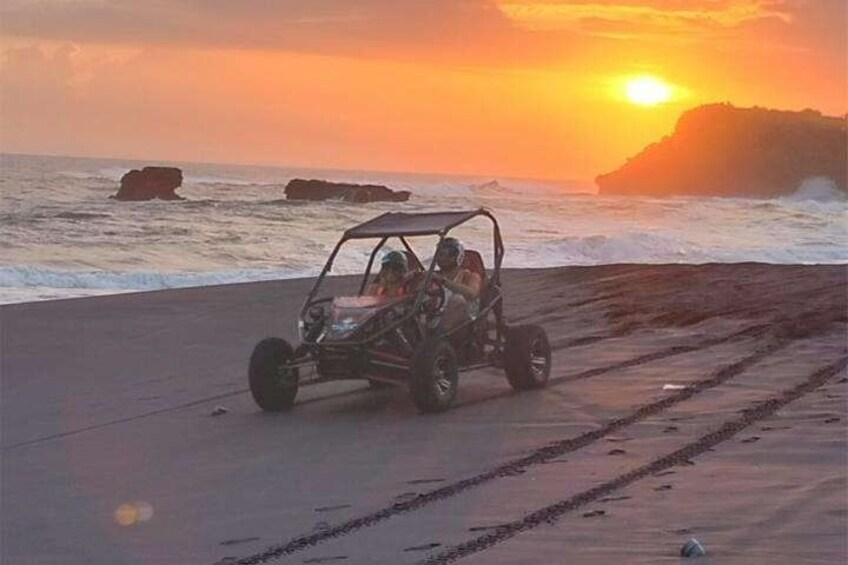 A dune buggy on a beach at sunset with waves in the background. 5