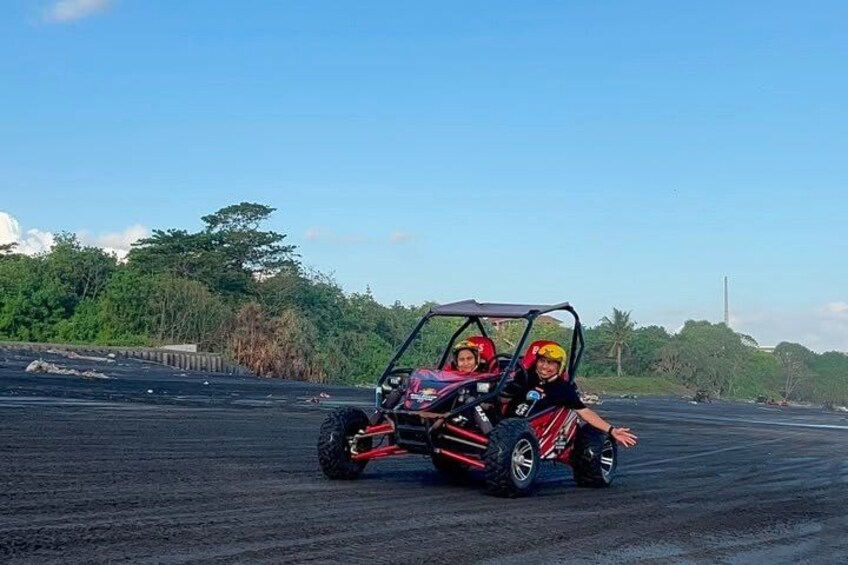 A red off-road vehicle on a paved surface with greenery in the background. 2