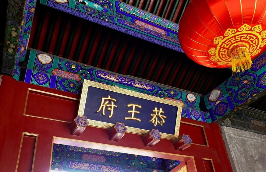 A traditional Chinese architectural structure with ornate decorations and a sign with Chinese characters. 1