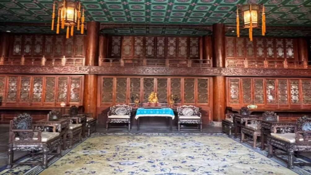 A traditional room with ornate wooden furniture, a patterned carpet, and a green ceiling with hanging lanterns. 4