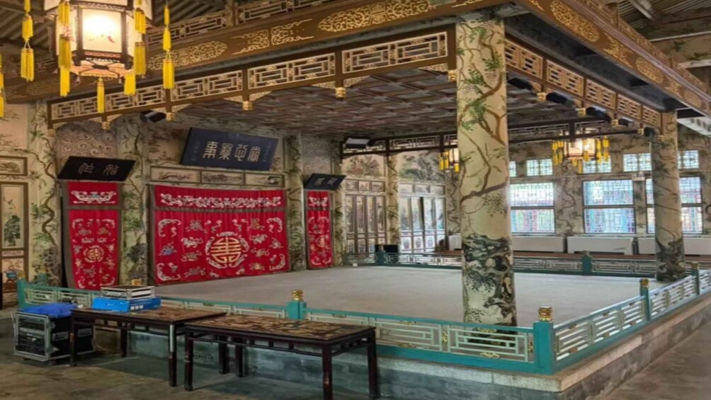 A traditional Chinese building with ornate decorations, red banners, and a large open space. 5