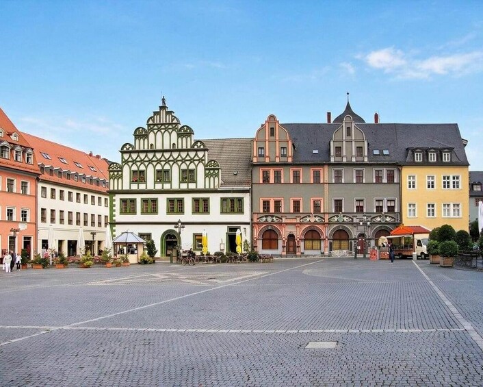 Une place pavée, bordée de bâtiments historiques, dont une église dotée d’un clocher imposant. 5