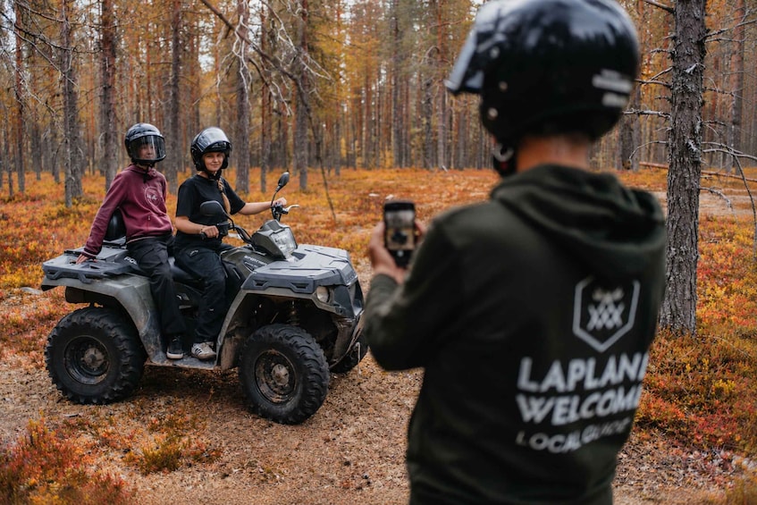 Deux personnes sur un véhicule tout-terrain dans une forêt, au milieu des feuilles d’automne. 3