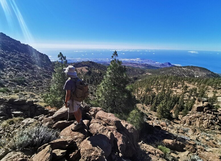 Ein Wanderer auf einem steinigen Bergpfad mit Blick auf eine Küstenlandschaft. 5