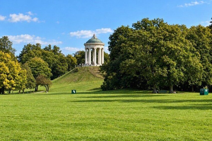 A park with a white gazebo, green grass, and trees. 5