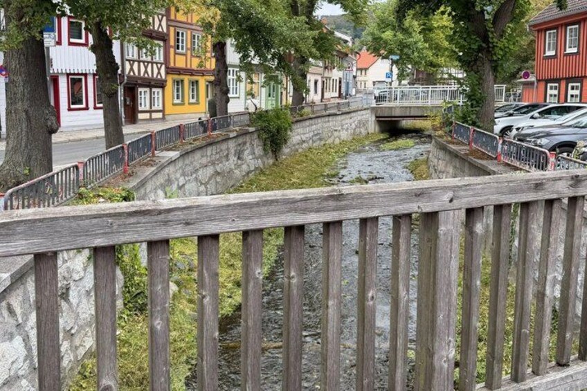 A wooden bridge over a river, colorful buildings, and parked cars. 3