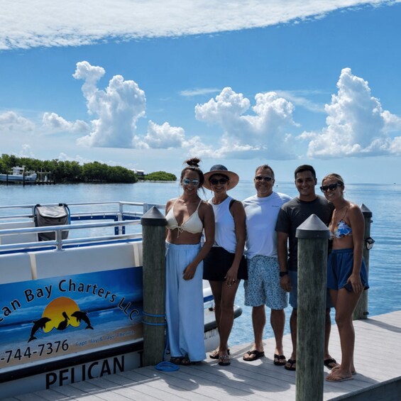 A group of people on a boat dock, with a clear sky and calm water. 1