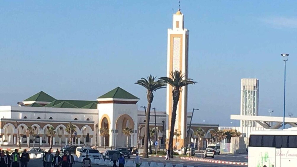 A mosque with a tall minaret, palm trees, and a modern building in the background. 4