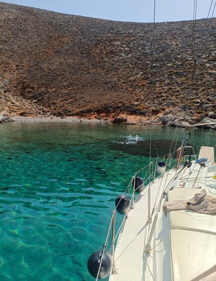 A boat anchored near a rocky shoreline with clear turquoise water. 4