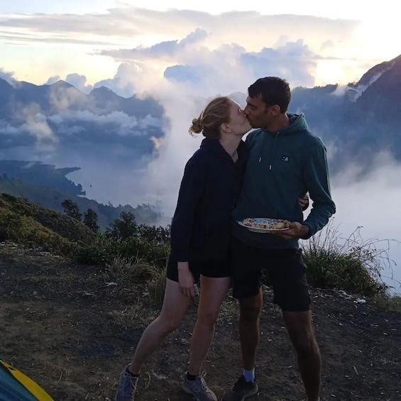 Un couple s'embrasse sur une montagne, surplombant une vallée enveloppée de nuages. 2