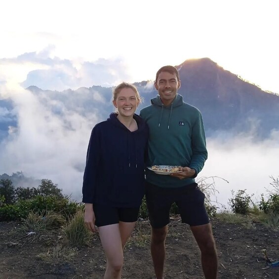 Deux personnes se tiennent debout sur une montagne, avec des nuages en arrière-plan. 5