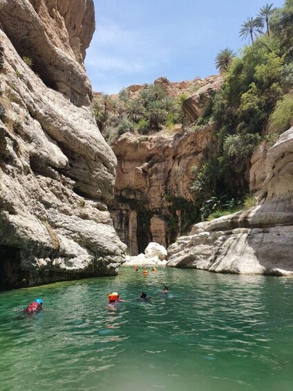 Ein tiefes Canyon mit steilen Felswänden und einem klaren Gewässer, in dem Personen Kajak fahren. 2