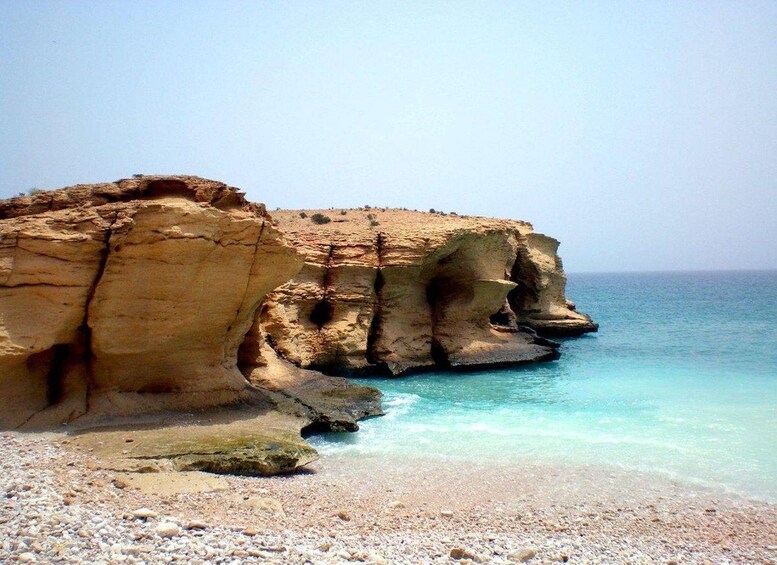 Eine Küstenlandschaft mit einer markanten Felsformation und klarem türkisblauem Wasser. 5