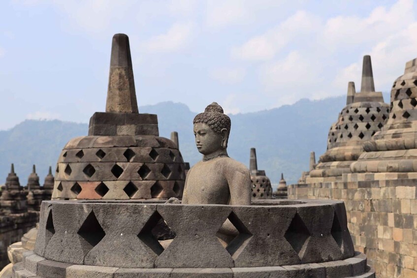 A stone Buddha statue in a niche surrounded by traditional stupa structures. 1