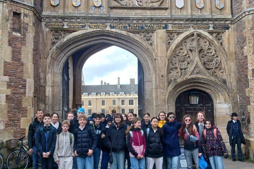 A group of people standing in front of a large stone archway with intricate carvings and inscriptions. 2
