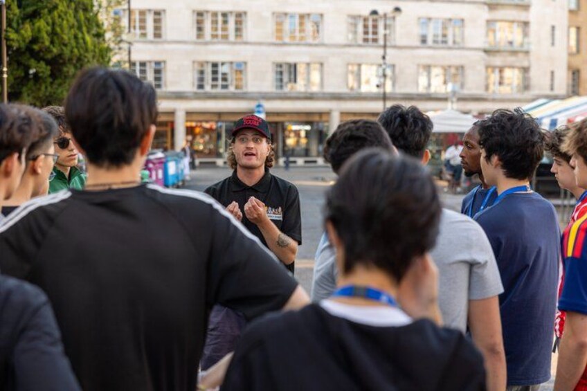 A group of people standing outdoors, engaged in a discussion. 4