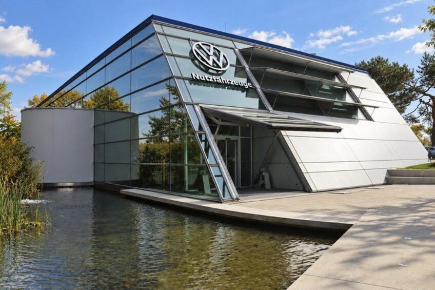 A modern building with a glass facade and a logo, situated next to a body of water. 4