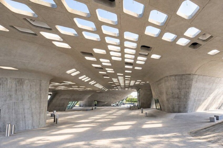 A modern architectural structure with a unique geometric ceiling design and concrete walls. 2