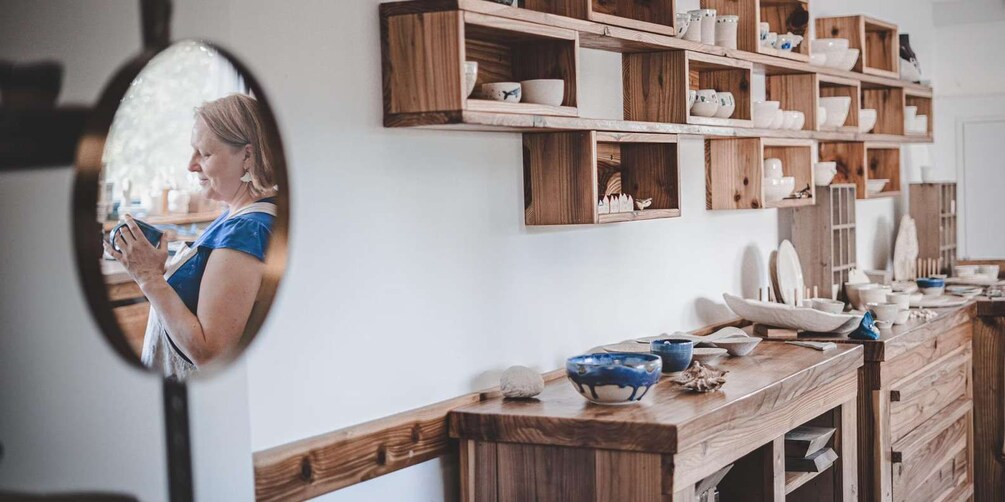 A kitchen with wooden shelves holding bowls and pottery. 5
