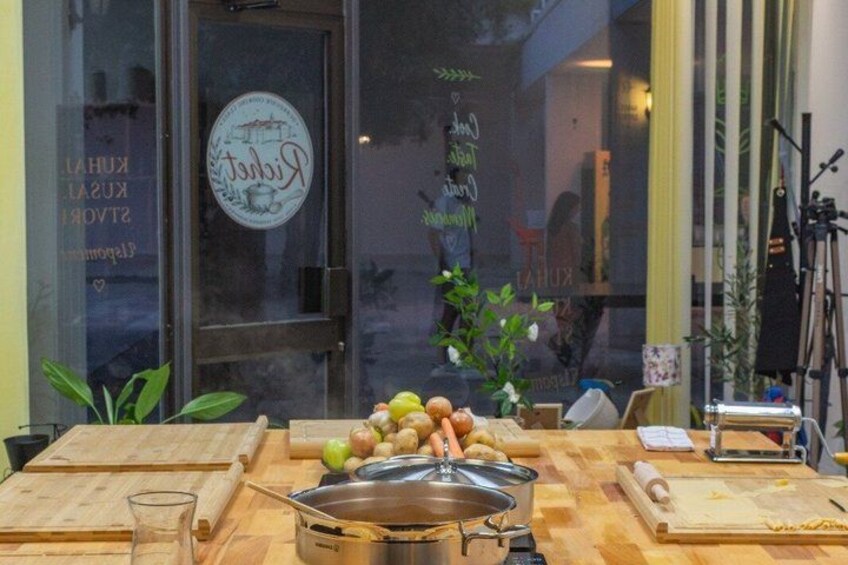 A kitchen counter with cooking utensils, a pot, and a cutting board. 1