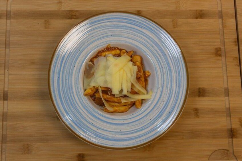 A plate of food with pasta and shredded cheese on a wooden table. 4