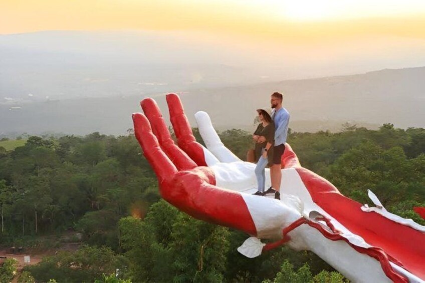 A couple standing on a large inflatable hand structure with a scenic landscape in the background. 2