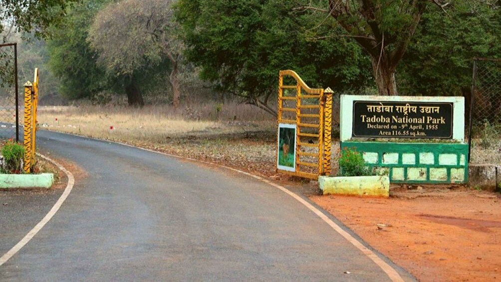 A road leading to Tadoba National Park with a signboard and a gate. 1