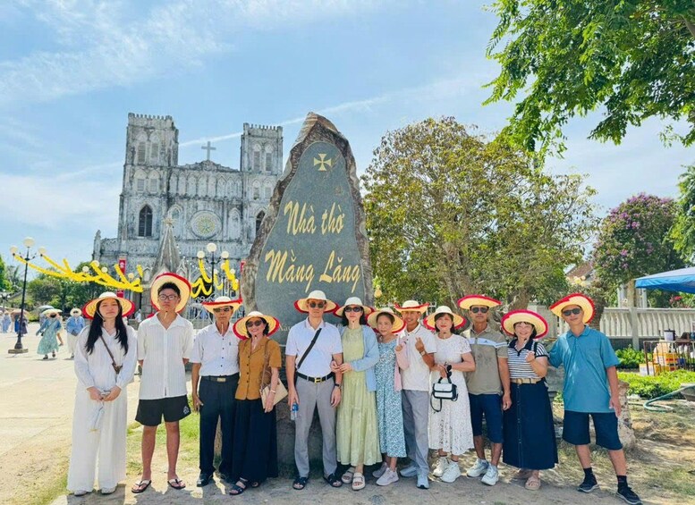 A group of people standing in front of a large stone with inscriptions, with a historic building in the background. 2