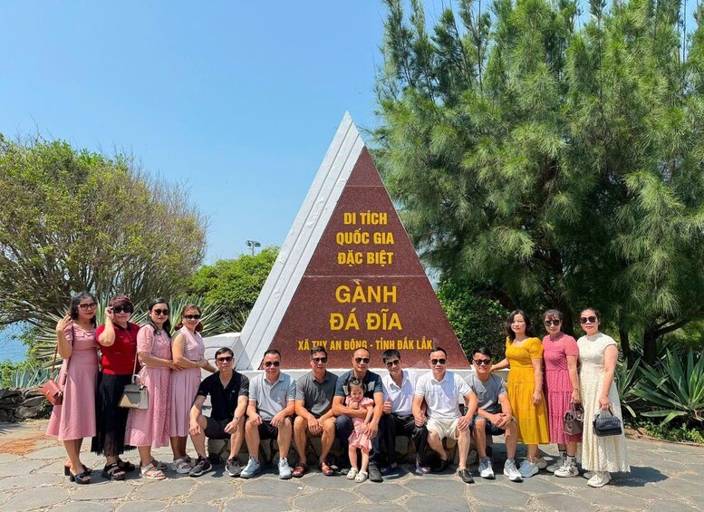 A group of people posing in front of a monument with inscriptions. 1