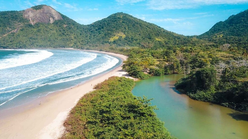 Un paysage côtier avec une plage de sable, une rivière et des collines verdoyantes. 1