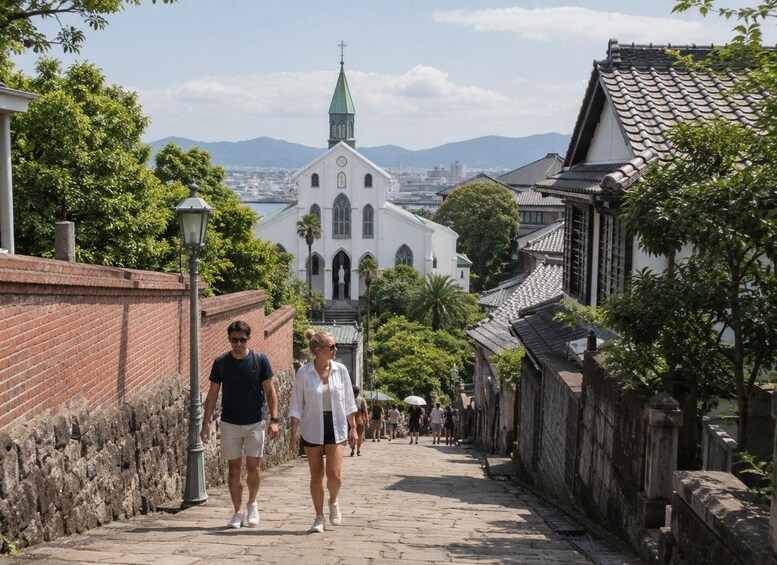 A cobblestone street lined with traditional buildings and a church with a green spire. 5