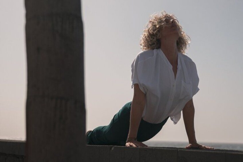 A person in a white shirt and green pants performing a push-up on a ledge. 4