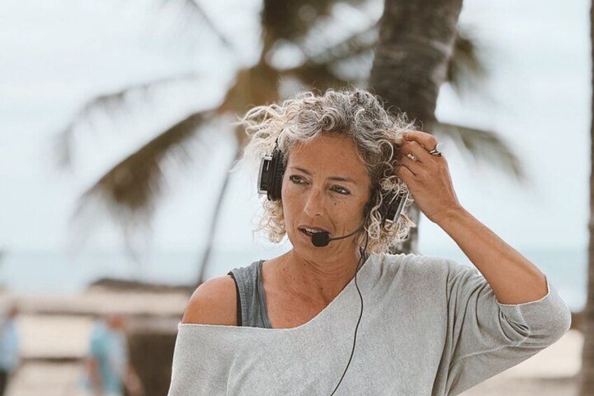 A person wearing headphones, standing outdoors with palm trees in the background. 5