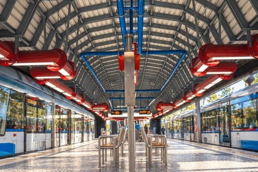 A train station with a covered platform, overhead lighting, and benches. 3