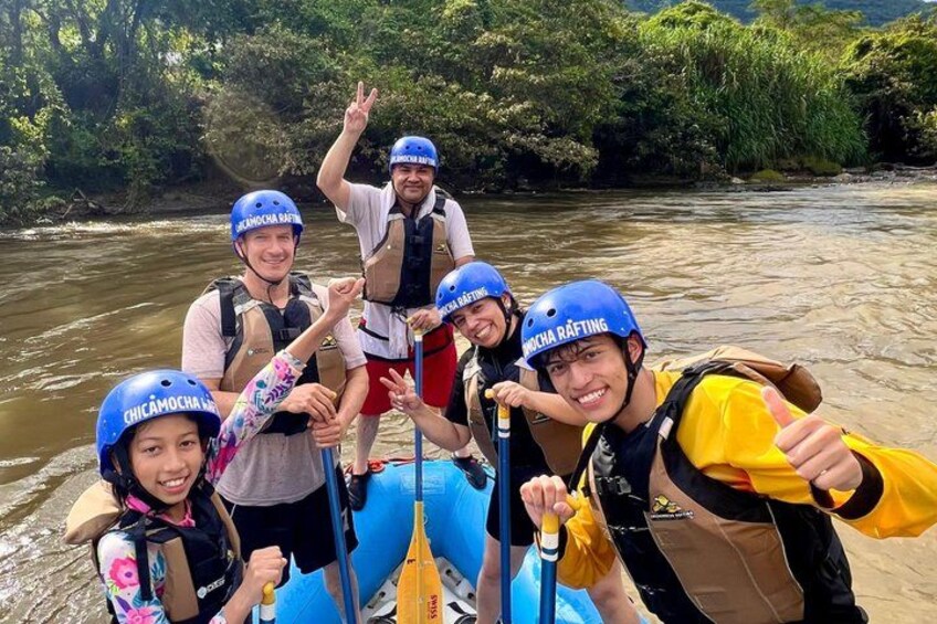 A group of people rafting on a river surrounded by greenery. 3