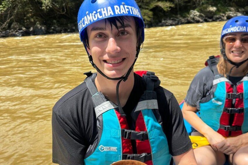 Two individuals wearing helmets and life jackets on a river. 2