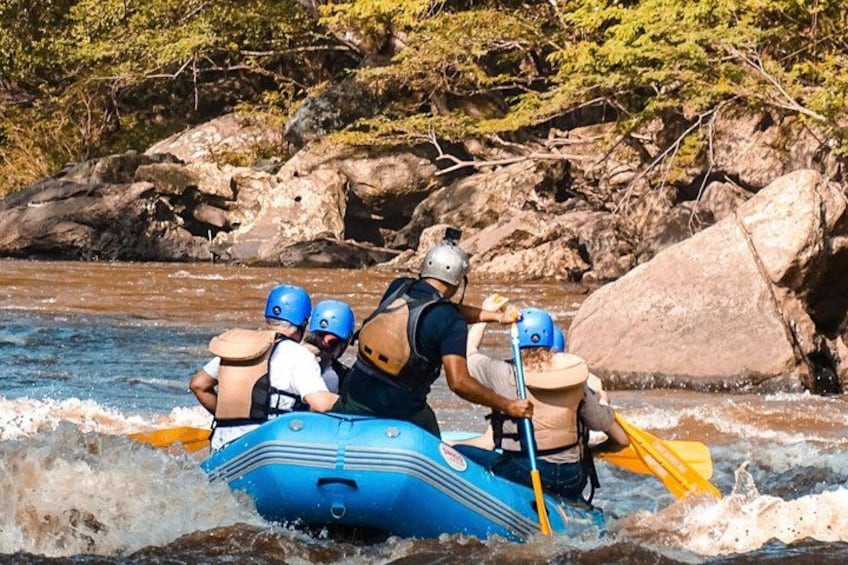 A group of people rafting on a river surrounded by rocks and trees. 1