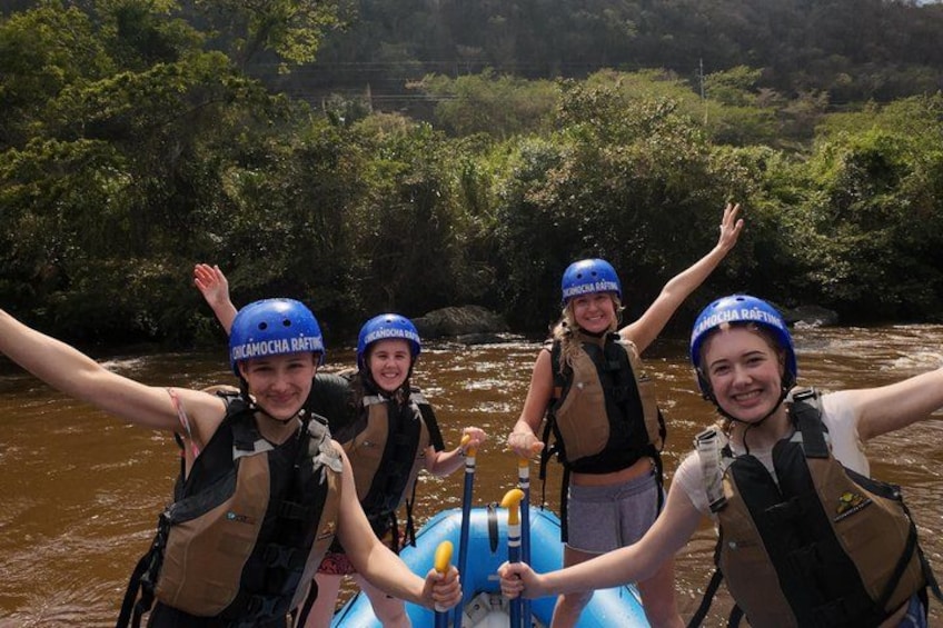 Four people rafting on a river, wearing helmets and life vests. 5