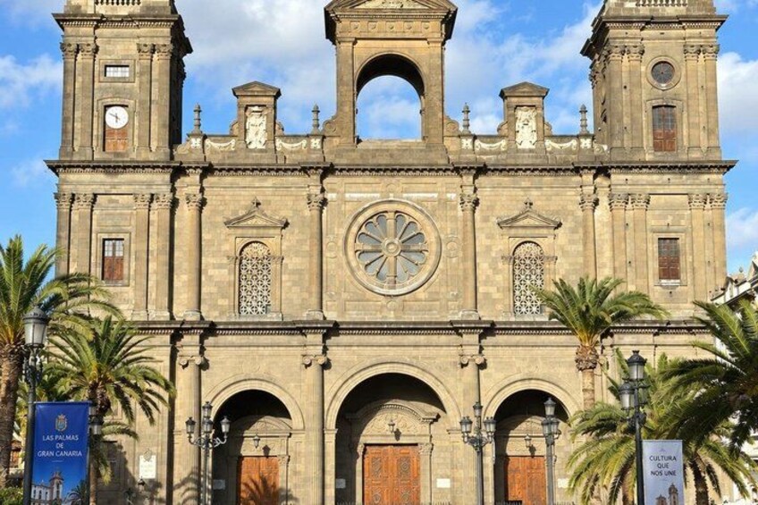 A historic church with a large circular window, arched doorways, and two bell towers. 5