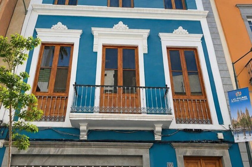 A building with blue and white exterior, wooden windows, and a balcony with metal railings. 3