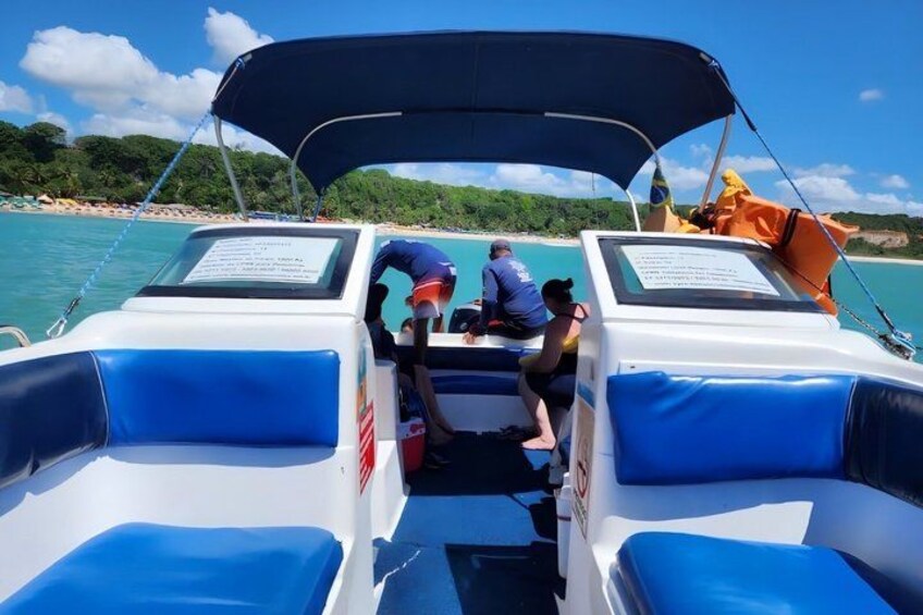 A boat with two blue cushioned seats, a person in a blue shirt, and a person in a black shirt. 5