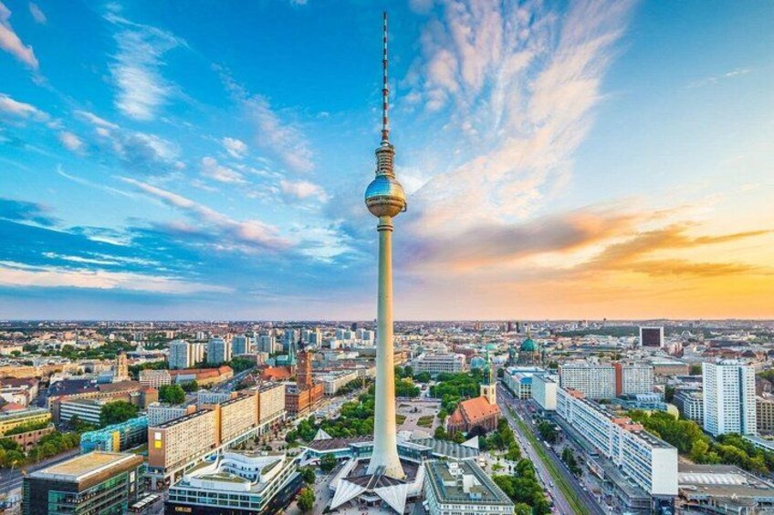 A cityscape with a prominent tower, modern buildings, and a clear sky. 1