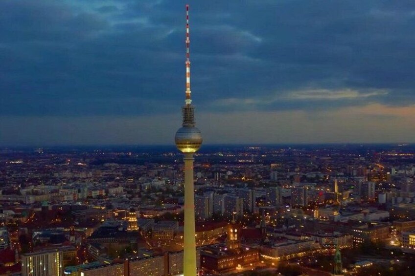 A cityscape with a prominent tower, likely a telecommunications tower, and a densely populated urban area with illuminated buildings. 2