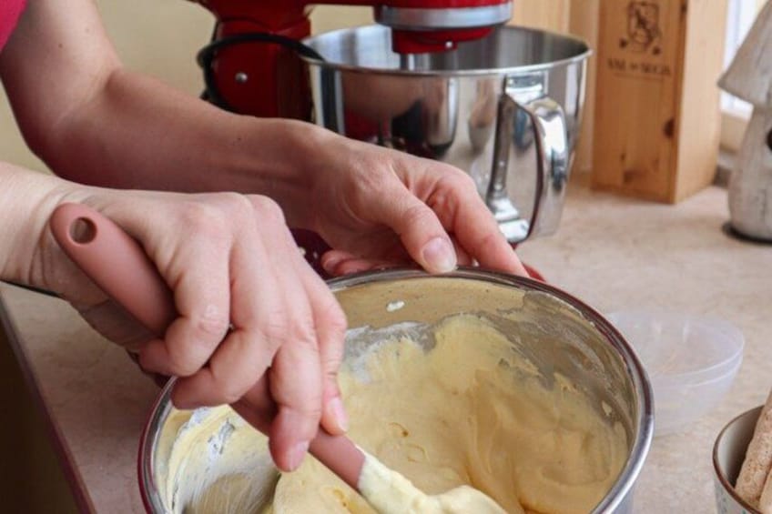 Hands mixing a creamy substance in a metal bowl. 5