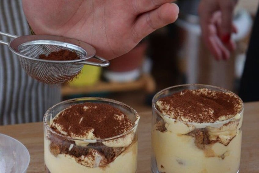 Two glasses of dessert with a layer of cream and a dusting of cocoa powder on top. 3